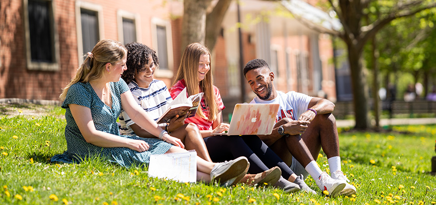 Group sitting outside doing group work on a laptop