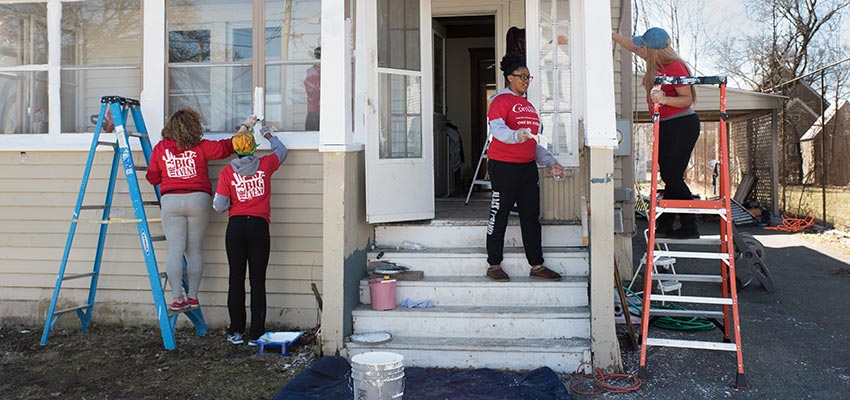 SUNY Cortland students help paint the exterior of a Cortland house during the Big Event