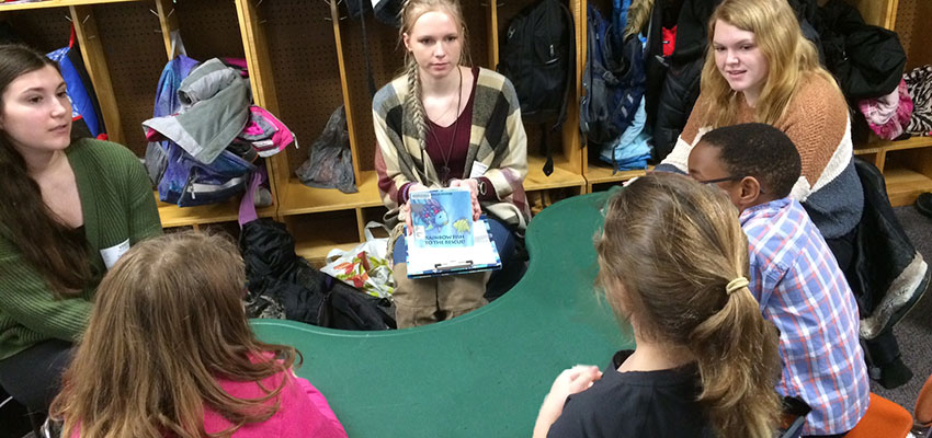 Students reading books and asking questions to local school children