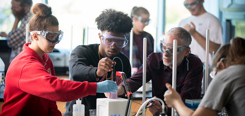 Students working with faculty member in chemistry lab