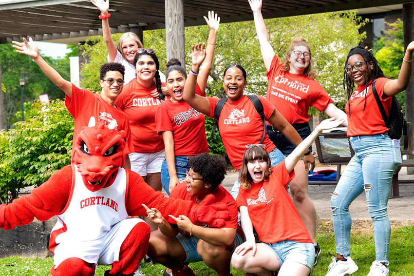 Blaze and a group of students all wearing Cortland red pose with arms up and open..