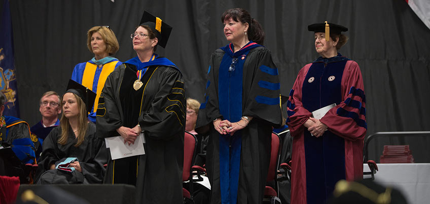 Staff standing on stage, in front of the audience