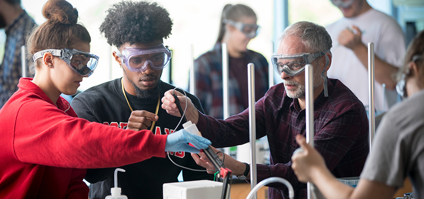 Chemistry professor assisting two students in a chemistry lab