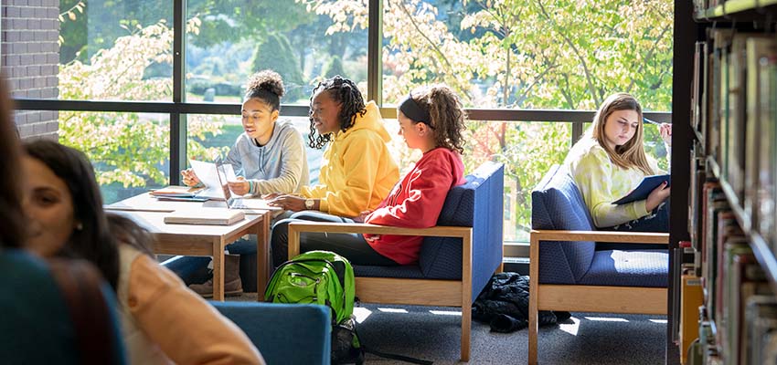 Students working together at a table near a window in Memorial Library.