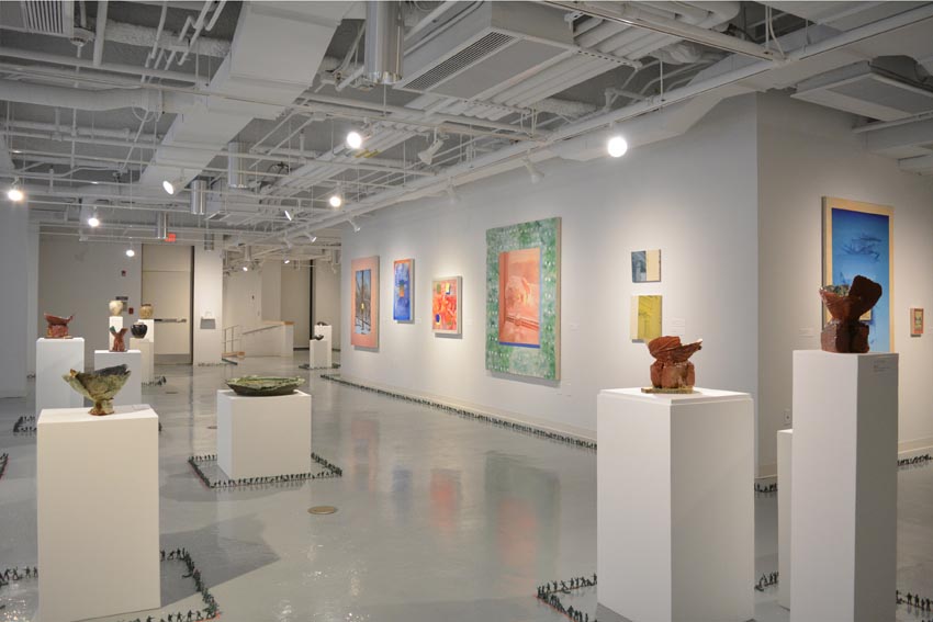 View into the central gallery at Dowd Gallery featuring sculptural objects produced by Jeremiah Donovan, professor of ceramics, Jillian McEvoy, instructor of ceramics, Jaroslava Prihodova, director of the Dowd Gallery, paintings by Stephen Alexander Clark, processor of painting, and floor installation by Bryan Valentine Thomas, instructor of design and drawing, at the Art and Art History Department.