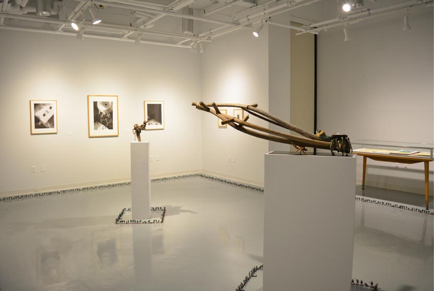 View into the west gallery at Dowd Gallery featuring sculptures produced by Scott Oldfield, instructor of drawing, prints by Charles Heasley, professor of printmaking and other courses, and floor installation by Bryan Valentine Thomas, instructor of design and drawing, at the Art and Art History Department. 