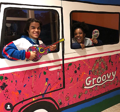 Students in a van created for a Woodstock-themed event in Neubig Dining